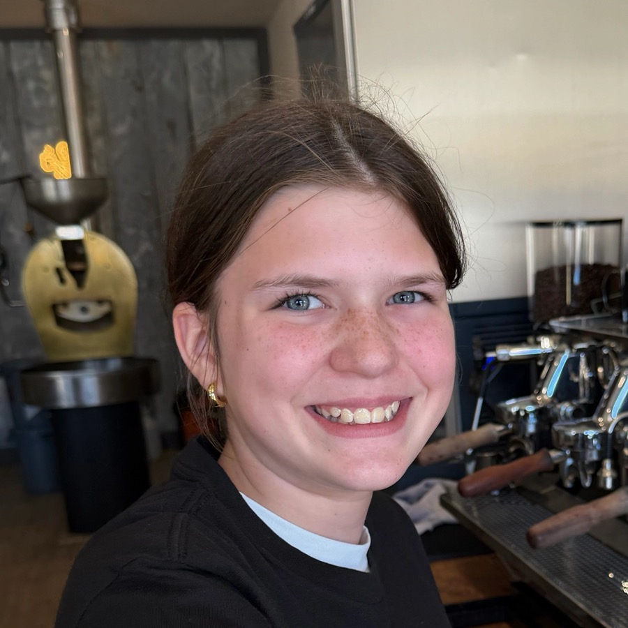 Young woman smiling in a cozy café with guitar decoration.